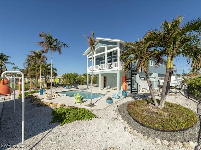 back of property featuring a patio, a fenced in pool, and a sunroom