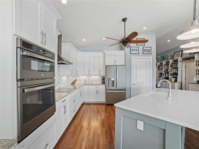 kitchen featuring sink, vaulted ceiling, a center island with sink, white cabinets, and appliances with stainless steel finishes