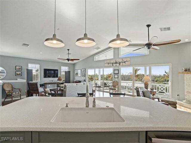 kitchen with ceiling fan, plenty of natural light, light stone countertops, and sink