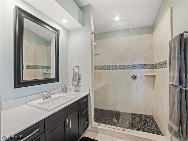 bathroom with tiled shower, vanity, and tile patterned flooring