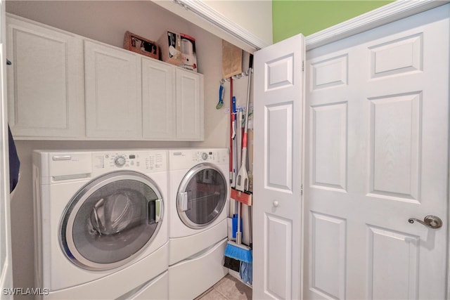 laundry area featuring cabinets, light tile patterned floors, and washer and clothes dryer