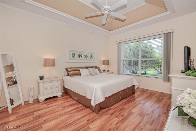 bedroom featuring light wood-type flooring, a raised ceiling, ceiling fan, and crown molding