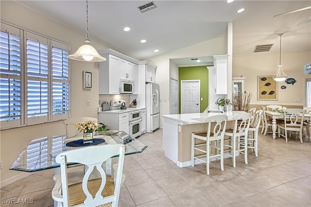 kitchen with range with electric stovetop, stainless steel fridge, white cabinets, and decorative light fixtures