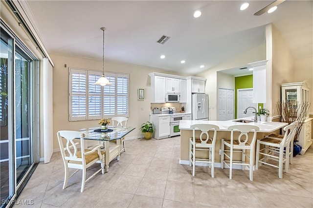 kitchen with white appliances, sink, decorative light fixtures, white cabinets, and lofted ceiling