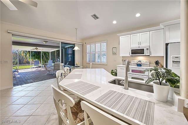 kitchen featuring white appliances, ceiling fan, white cabinets, hanging light fixtures, and light tile patterned flooring