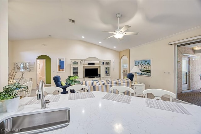 kitchen with crown molding, sink, vaulted ceiling, ceiling fan, and light stone countertops