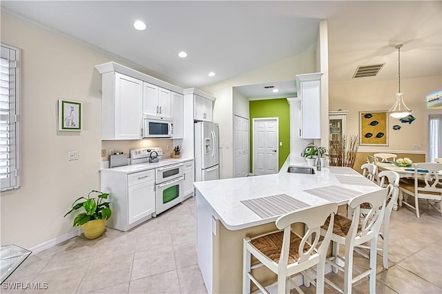 kitchen with pendant lighting, white appliances, white cabinets, sink, and kitchen peninsula