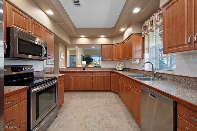 kitchen with backsplash, light tile patterned floors, sink, and appliances with stainless steel finishes