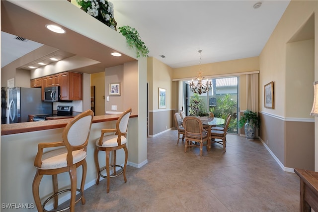 kitchen with a breakfast bar, appliances with stainless steel finishes, decorative light fixtures, and a notable chandelier