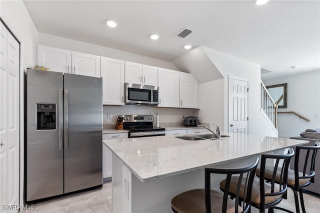 kitchen with sink, white cabinetry, stainless steel appliances, and an island with sink