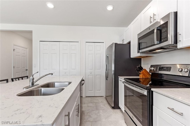 kitchen with white cabinets, sink, light tile patterned floors, light stone counters, and stainless steel appliances