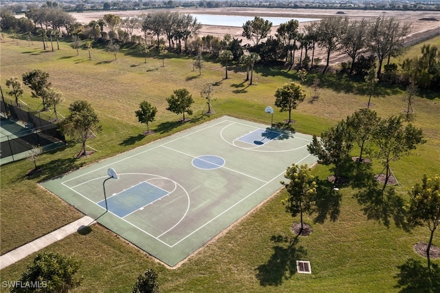 view of sport court with a water view and a yard