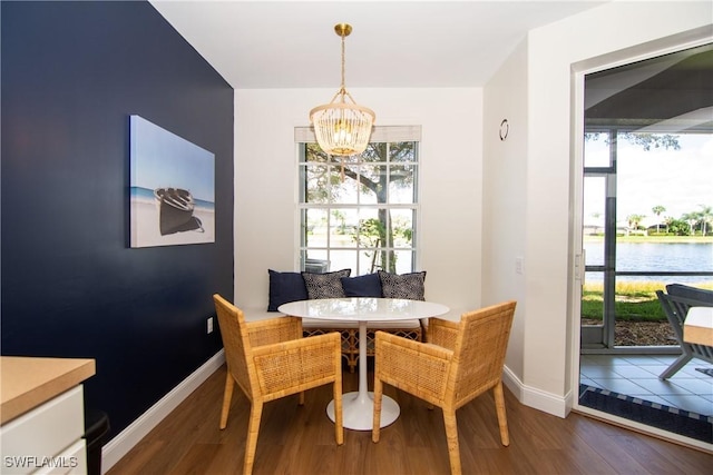 dining space featuring a notable chandelier, dark hardwood / wood-style floors, and a water view