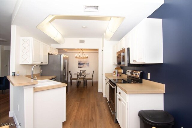 kitchen featuring kitchen peninsula, white cabinetry, pendant lighting, and stainless steel appliances