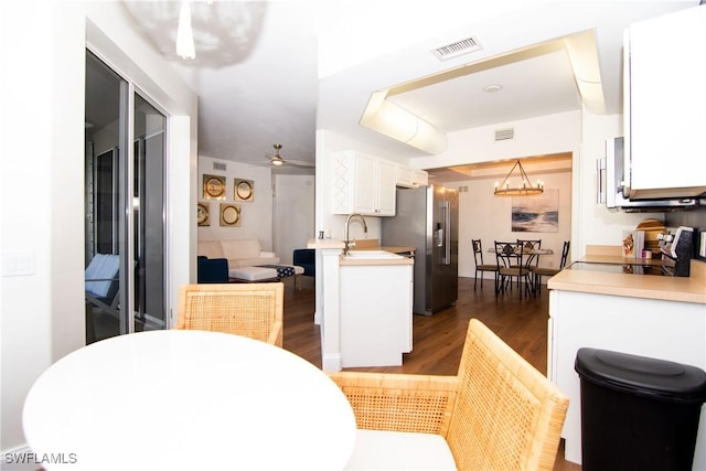 kitchen featuring stove, dark hardwood / wood-style flooring, high quality fridge, ceiling fan with notable chandelier, and white cabinetry