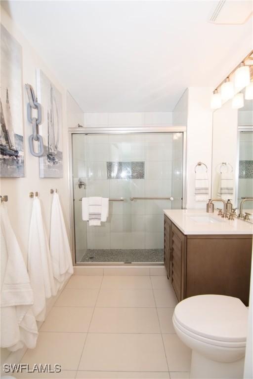 bathroom featuring tile patterned floors, vanity, toilet, and a shower with shower door