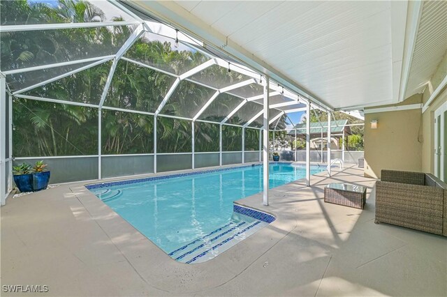 view of swimming pool featuring glass enclosure and a patio