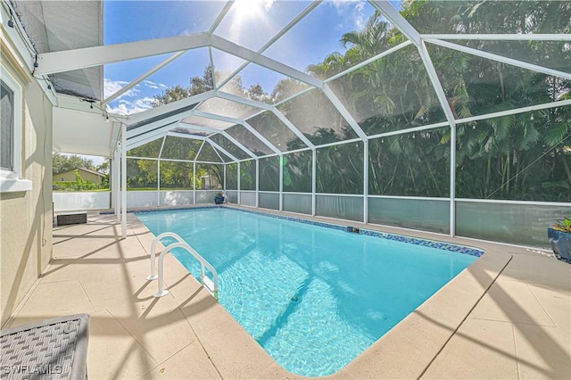 view of pool with glass enclosure and a patio