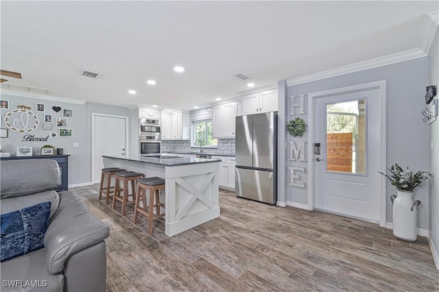 kitchen with stainless steel appliances, white cabinets, a breakfast bar, and a kitchen island