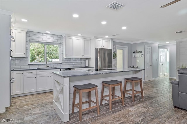 kitchen featuring white cabinetry, a kitchen island, and stainless steel fridge