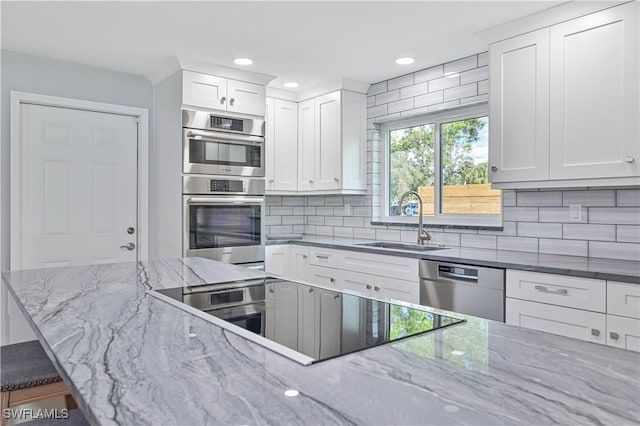 kitchen featuring tasteful backsplash, sink, white cabinetry, appliances with stainless steel finishes, and dark stone counters