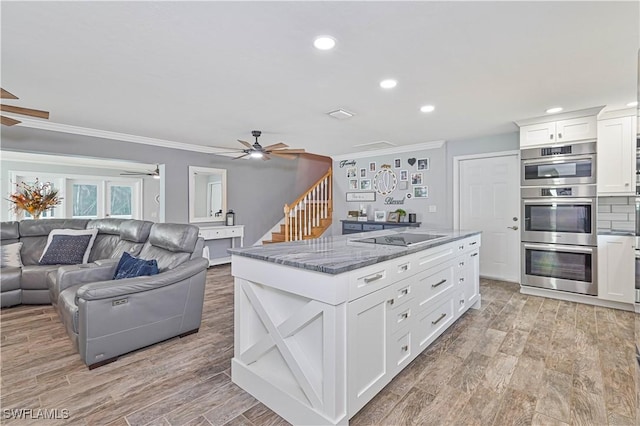 kitchen featuring white cabinetry, ceiling fan, black electric cooktop, dark stone counters, and double oven