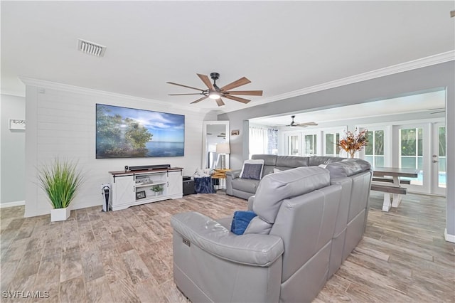 living room with light wood-type flooring, a wealth of natural light, and crown molding