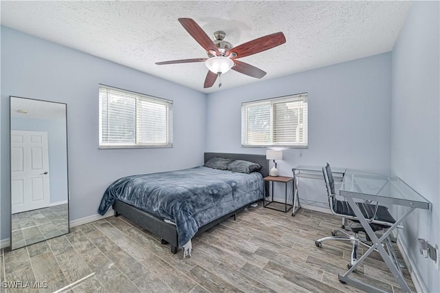 bedroom featuring ceiling fan, multiple windows, and a textured ceiling