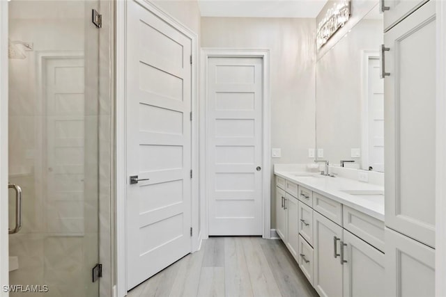 bathroom with hardwood / wood-style floors, vanity, and a shower with shower door