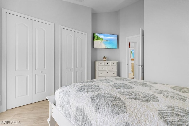 bedroom with two closets and light wood-type flooring