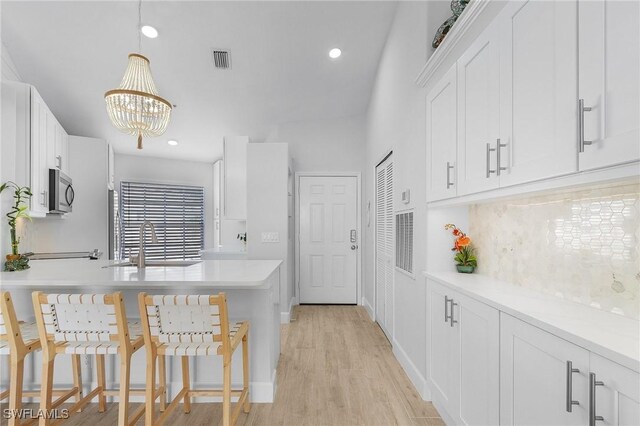 kitchen with pendant lighting, white cabinetry, sink, and tasteful backsplash