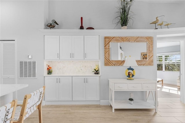 interior space featuring backsplash, white cabinetry, and light hardwood / wood-style floors