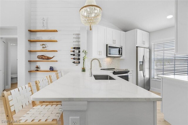 kitchen with sink, hanging light fixtures, stainless steel appliances, kitchen peninsula, and a kitchen bar