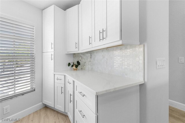 kitchen featuring light stone countertops, white cabinets, and light wood-type flooring