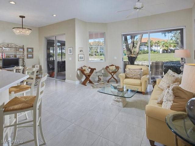 living room featuring ceiling fan with notable chandelier and a healthy amount of sunlight