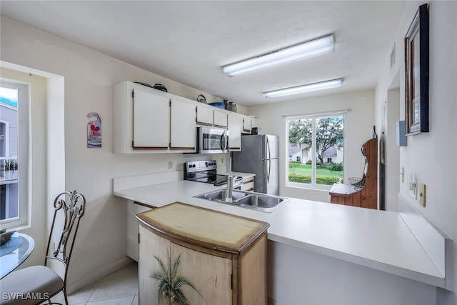 kitchen featuring kitchen peninsula, white cabinetry, light tile patterned flooring, and stainless steel appliances