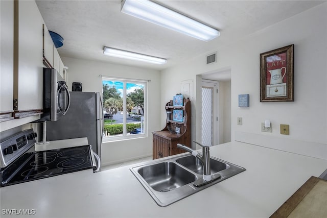 kitchen featuring white cabinets, kitchen peninsula, range with electric stovetop, and sink