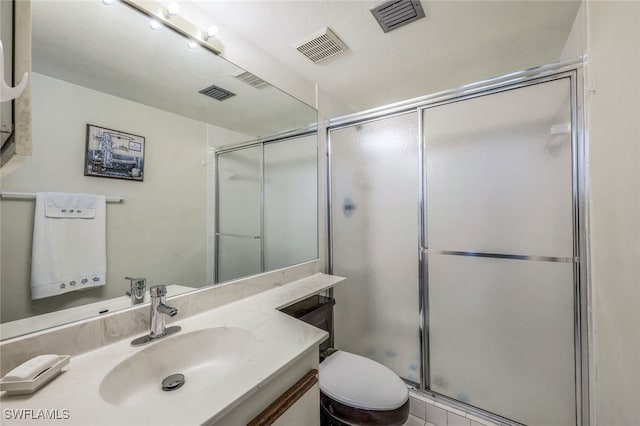 bathroom featuring vanity, toilet, and a shower with shower door