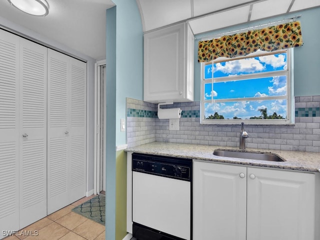 kitchen with dishwasher, light tile patterned floors, white cabinetry, and sink