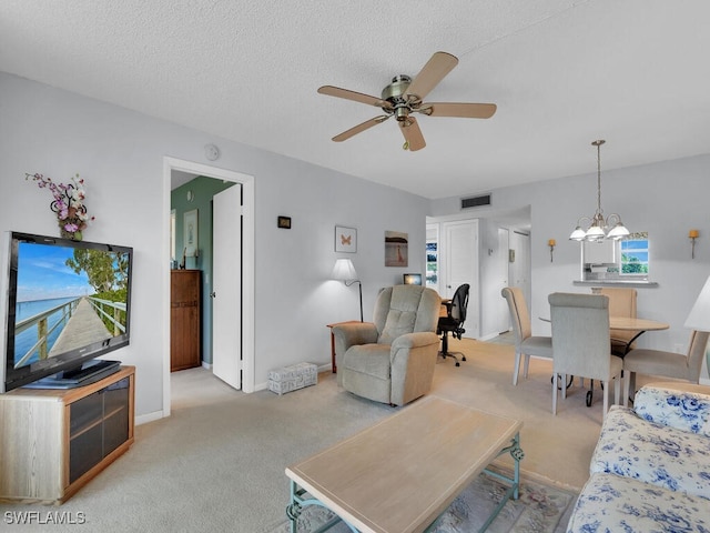 living room with a textured ceiling, ceiling fan with notable chandelier, and light carpet