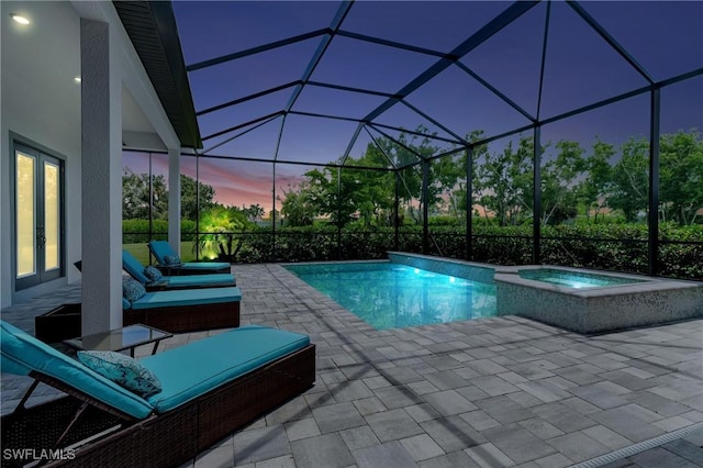 pool at dusk featuring an in ground hot tub, a patio, and a lanai