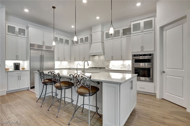 kitchen featuring white cabinets, an island with sink, pendant lighting, and appliances with stainless steel finishes