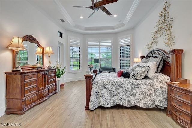 bedroom with a raised ceiling, multiple windows, ceiling fan, and light wood-type flooring