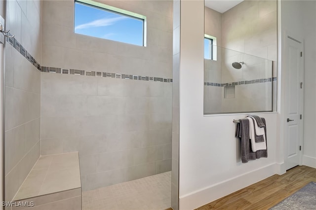 bathroom with tiled shower and hardwood / wood-style flooring