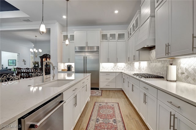 kitchen featuring backsplash, sink, appliances with stainless steel finishes, decorative light fixtures, and white cabinetry