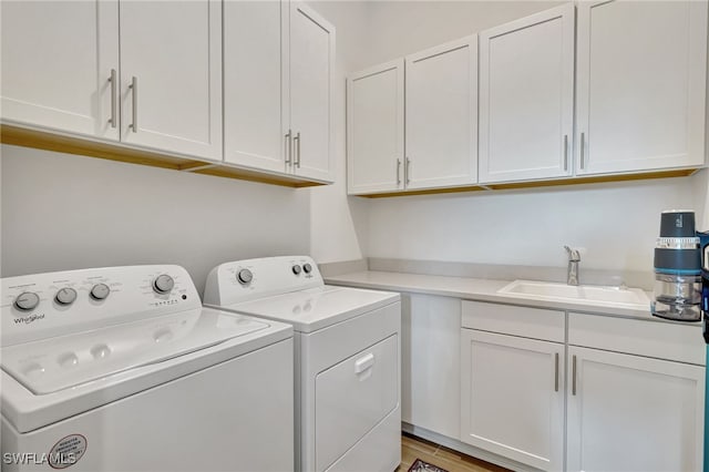 laundry room featuring washing machine and clothes dryer, light hardwood / wood-style floors, cabinets, and sink