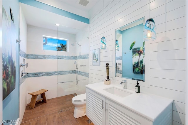 bathroom featuring vanity, toilet, hardwood / wood-style floors, and a tile shower