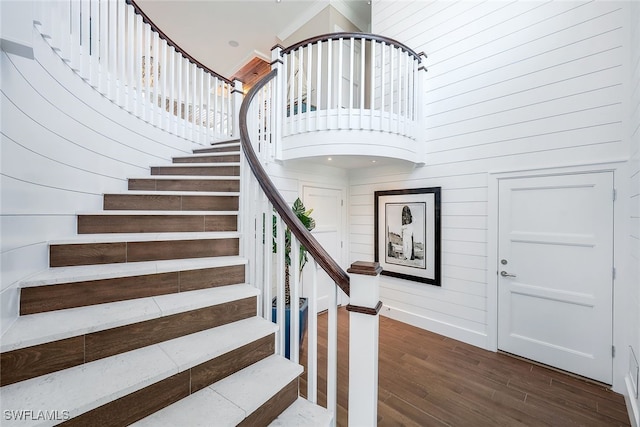 stairs with hardwood / wood-style floors, ornamental molding, and a high ceiling