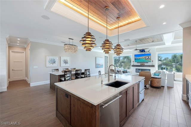 kitchen with sink, crown molding, an island with sink, decorative light fixtures, and stainless steel dishwasher