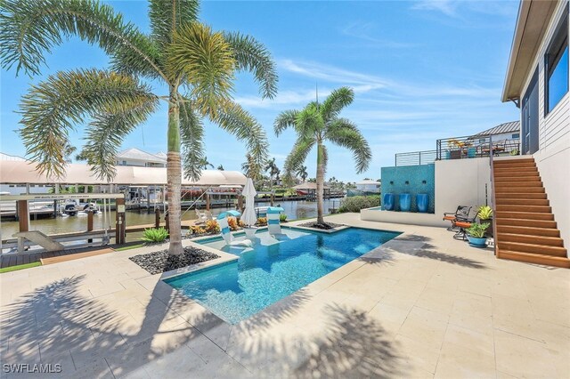 view of swimming pool with a patio area, a water view, a bar, and a dock